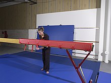 Entraîneur de gymnastique fixant une enveloppe en mousse à la poutre d'équilibre.