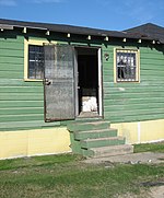 Screen door of a flood-damaged house, in Desire, New Orleans, after Hurricane Katrina, 2006 DesireGreenHouseDoorway.jpg