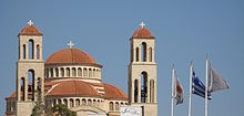 Flags of Greece and Cyprus being flown on flagpoles with cross finials in front of Agioi Anargyroi Church, Pafos. Greece Cyprus flags cross finials Agioi Anargyroi Pafos.jpg
