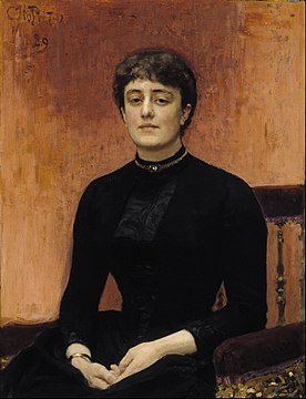 Portrait d'une femme assise, habillée en noir, de face.