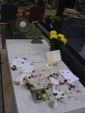 Marble grave stone with mementoes, flowers, notes and other small items placed on it.