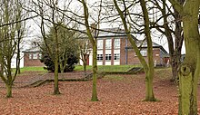 A photograph of Lisburn Central Primary School from behind, with trees covering it.