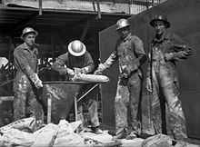 Several Workmen wearing ribbed metal hard hats, and one (right) in a MSA Skullgard, at the site of a Texas oil well in 1940 Men in Work Clothes.jpg