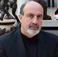 Image of Nassim Nicholas Taleb from the——shoulders up. He has receding hair. And a short mostly white beard.