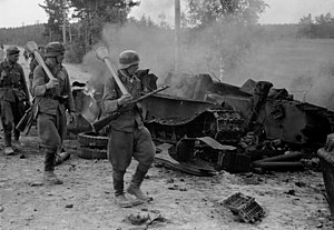 Jalkaväkirykmentti 12:n miehet ohittavat saksalaisen rynnäkkötykin tuhoaman T-34-tankin 30. kesäkuuta 1944. Vasemmalla panssarijääkäri Eino Heikkilä, edessä panssarinyrkit olallaan kersantit Kalle Niemelä ja Heino Nikulassi. Nikulassi kaatui kuvaamista seuraavana päivänä.