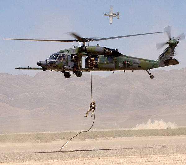 An HH-60G Pave Hawk retrieves a pararescueman as an A-10 Thunderbolt II provides cover fire during a firepower demonstration on the Nellis bombing ran