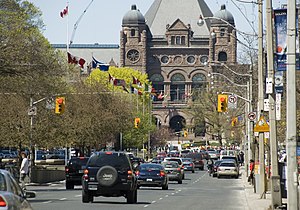 A busy urban boulevard, with Queen's Park visible in the background.