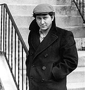 Photo en noir et blanc d'un homme portant un manteau et une casquette