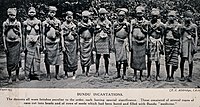 Murrosikäisiä tyttöjä, joita ollaan vihkimässä sandeen Sierra Leonessa. Teksti suomennettuna: ”Kaikki tanssijat pitivät järjestyksessä omalaatuisia taikaesineitä, joilla jokaisella oli erityinen tarkoitus. Nämä taikaesineet koostuivat useista korsista leikattuina helmiksi ja siemenriveistä, jotka oltiin rei’itetty ja täytetty bundun (sanden) ’lääkkeillä.’”