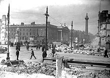 Černobílá fotografie Nelsonova sloupu mezi ruinami Velikonočního povstání z roku 1916.