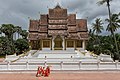 Buddhist monks walking in front of the temple Haw Pha Bang in Luang Prabang.jpg