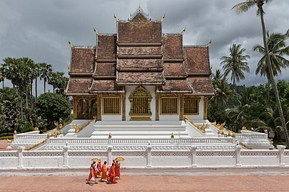 Buddhist monks walking in front of the temple Haw Pha Bang in Luang Prabang