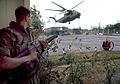 A Marine provides security as helicopters land at the DAO Compound