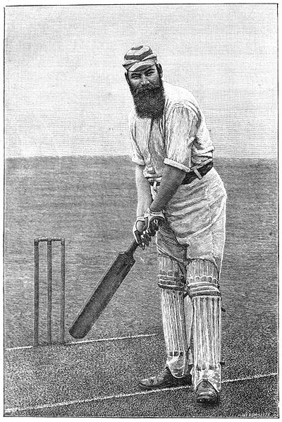 W.G. Grace (a tall man with a large bushy beard), dressed in cricket whites and holding a cricket bat in front of a wicket, left foot forwards