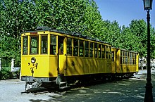 gelb lackierter Straßenbahntriebwagen mit gleichfarbigem Beiwagen, als Denkmal in einem Park in Granada aufgestellt