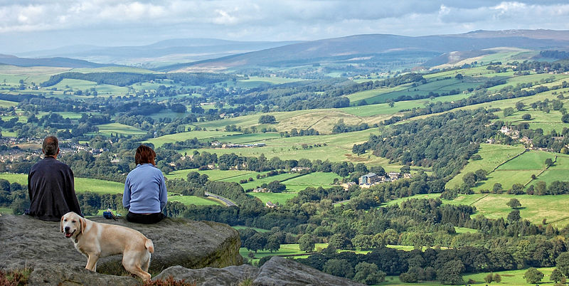 A couple sit and watch the world go by on the rocky outcrop at Woodhouse, Ilkley Moor