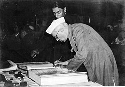 A bespectacled Jawaharlal Nehru bending over a large book