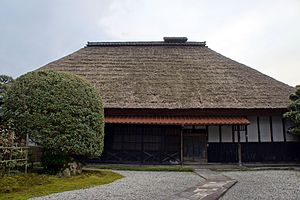 Large wooden house with thatched roof.