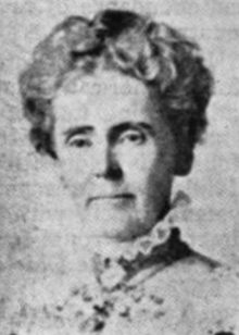O femeie albă mai în vârstă, cu părul cenușiu, într-un capăt creț, purtând un guler înalt și un cameo sau o broșă la gât