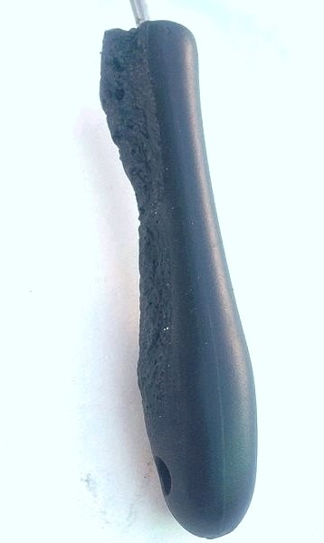 A plastic handle from a kitchen utensil, deformed by heat and partially melted