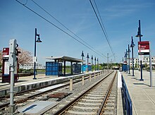 Sidoplattformarna på Mt.  Hood Avenue station;  plattformarna består av blå lampor och den vänstra innehåller ett skydd