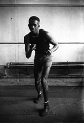 Photographie en noir et blanc d'un boxeur longiligne en garde basse.