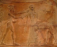 Perseus solda duruyor ve başını çevirirken kılıcını savurarak Medusa'yı bir örgüden tutuyor.