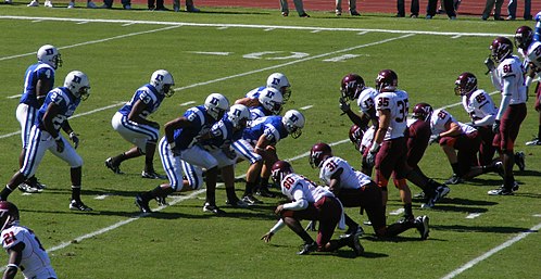 In the traditional or "cup" punt formation, the long snapper is the center of the interior line (#58 in blue)