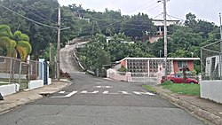 Road going up between colorful houses on either side, mountain in back