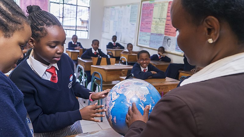 File:Teacher points out a country on a map.jpg