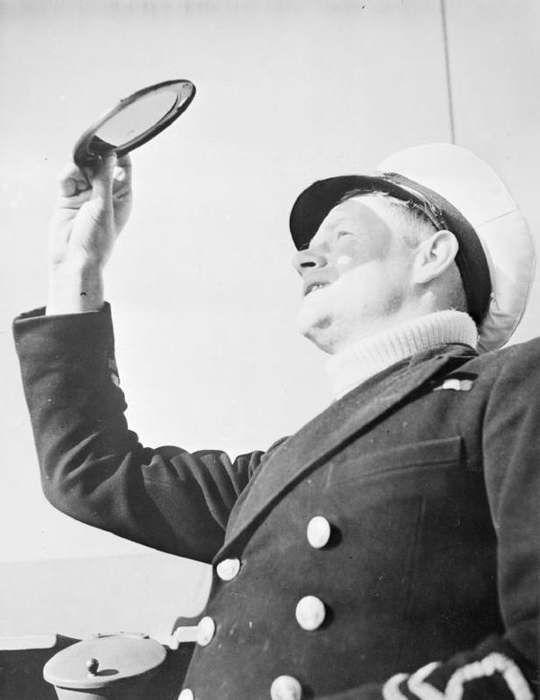 A portrait of a New Zealand Merchant Navy captain of a Fairmile 'submarine chaser', as he holds up and looks through a small coloured screen. This dis