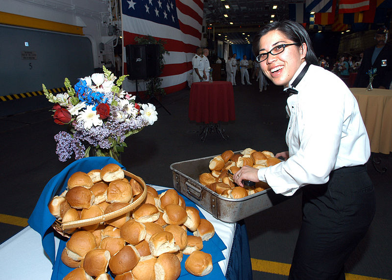 File:US Navy 060528-N-1371G-039 Culinary Specialist 3rd Class Siriphone Phakdy places fresh rolls on one of the reception tables set up in the hangar bay of the amphibious assault ship, USS Kearsarge (LHD 3).jpg