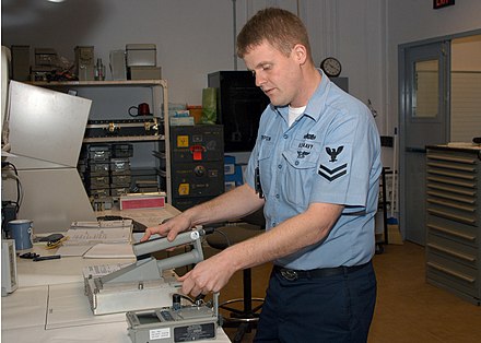 Hand-held large area alpha scintillation probe under calibration using a plate source in close proximity to the detector. US Navy 070208-N-9132D-002 Electronics Technician 2nd Class Shea Thompson tests an Alpha Particle Dection Probe.jpg