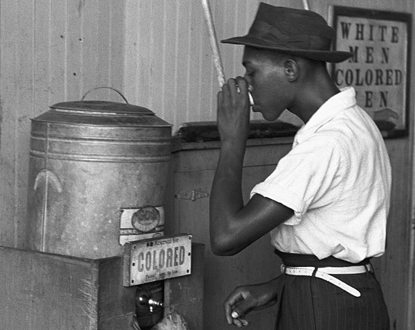 An African American man drinking at a "colored" drinking fountain in a streetcar terminal in Oklahoma City, 1939