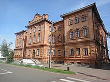 Photographie en contre-plongée d'un bâtiment marron de style néo-russe avec deux étages en plus du rez-de-chaussée.