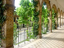 Photographie de 2011 d'un couloir du lycée, laissant voir les arcades, de la verdure et la cour de récréation.