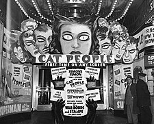 An entrance to a movie theatre adored with display art featuring people with demonic eyes and promotional text for Cat People.