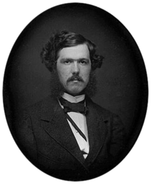 Black-and-white photograph of a young man with a mustache