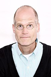 photo en couleur d'un homme chauve avec des lunettes