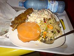 Riso fritto nigeriano con pesce, insalata e pudding al vapore di fagioli