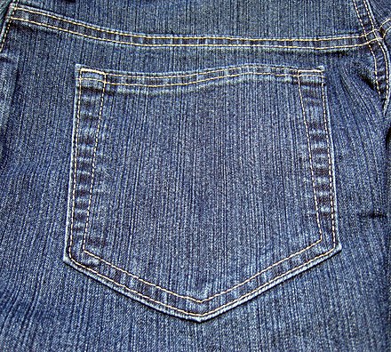 Patch pocket with topstitching and bar tacking on the back of a pair of blue jeans.
