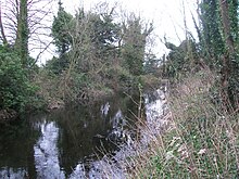 Stratton Park Moated Enclosure gegenüber dem Eingang mit Damm.JPG