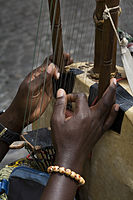 Black hands playing the strings of a 21 string Kora harp-lute, an African musical instrument, Rome, Italy