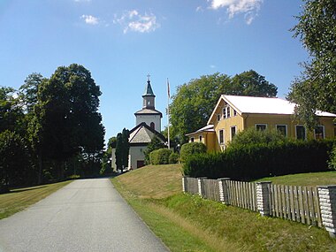 Kyrkan från öster med det gula sockenstugan (församlingshemmet) till höger.