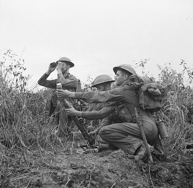 A 2-inch mortar team of the 2nd Battalion, East Lancashire Regiment, keep up covering fire during the advance on Pinbaw, December 1944.
