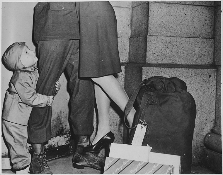 File:A Youngster, Clutching His Soldier Father, Gazes Upward While the Latter Lifts His Wife from the Ground to Wish Her a "Merry Christmas" (3678706327).jpg