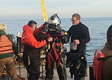 Coworkers inspect a diver in a positive pressure dive suit prior to conducting dive operations as a response to the shipwreck on November 24, 2015. Argo shipwreck dive operations 2015.jpg