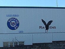 Rear view of the Brewery Field's west stadium displaying the Bridgend Ravens insignia in 2006