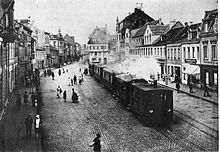 A steam tram engine from the Cologne-Bonn Railway, pulling a train through Bruhl marketplace, c. 1900 Bruehl Feuriger Elias.jpg
