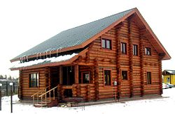 Two-story log house in winter, with sloping roof